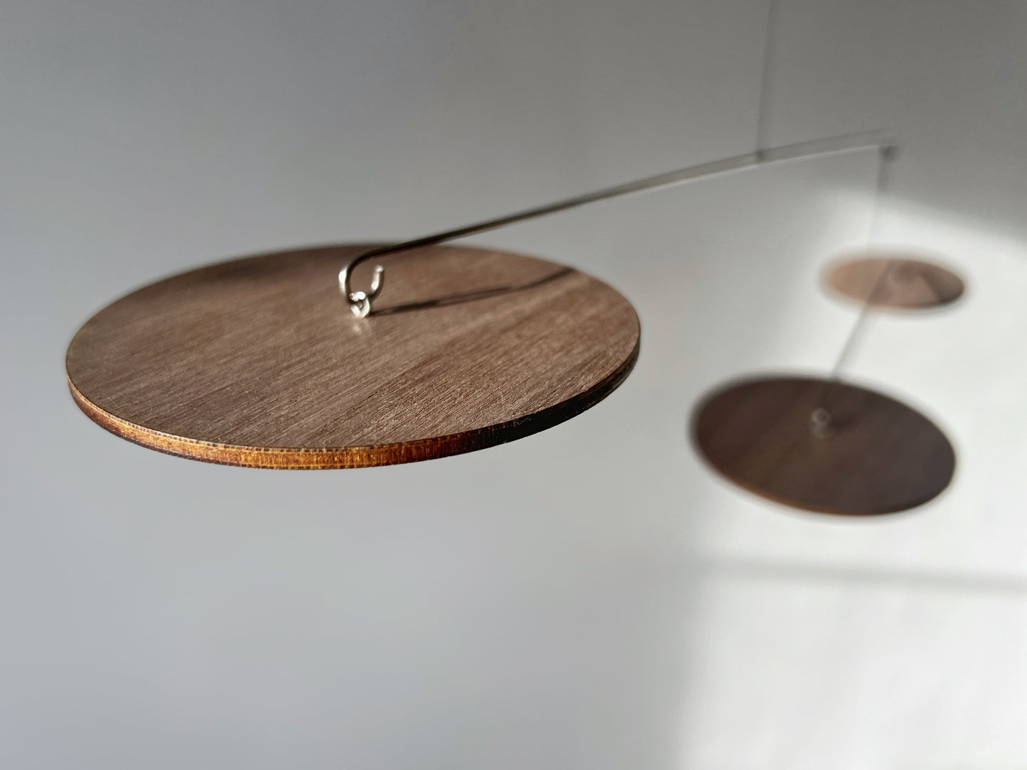 A handcrafted wooden mobile — a modern mobile, inspired by Alexander Calders’ mobile kinetic sculptures for mid century decor lovers. This elegant hanging mobile is a piece of moving art and a mobile for adults, bringing calm motion, balance, and timeless design to your home.
This mid century mobile is a beautifully balanced kinetic mobile, art mobile, and large mobile that drifts gracefully with the air. Handcrafted from fine walnut veneer and stainless steel wire, it combines organic warmth with minimali