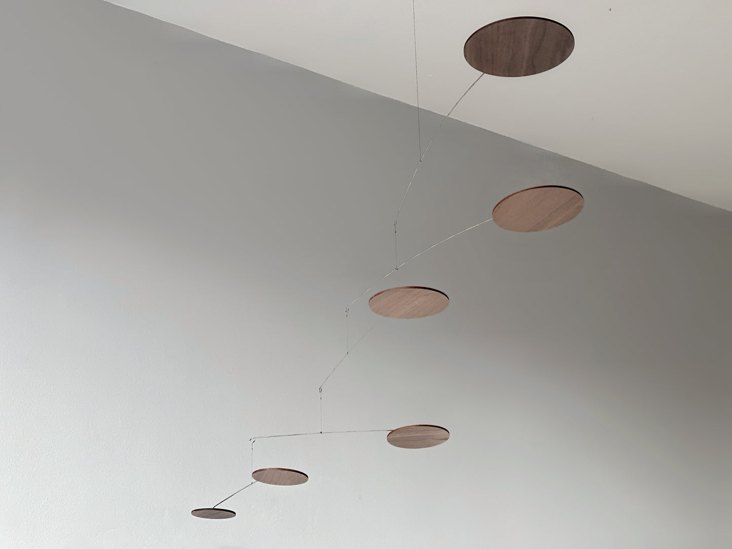 handcrafted walnut mobile by The Illuminist. This elegant modern mobile is made from walnut veneer wooden discs, stainless steel wire, carefully balanced to create gentle, floating motion. it’s the perfect piece of designer home decor for modern interiors. Inspired by Alexander Calder’s mobiles, The Orbit blends art and engineering to form a serene kinetic sculpture that transforms as it moves with the air. make it ideal for mid century decor, Scandinavian design, or any minimalist decor