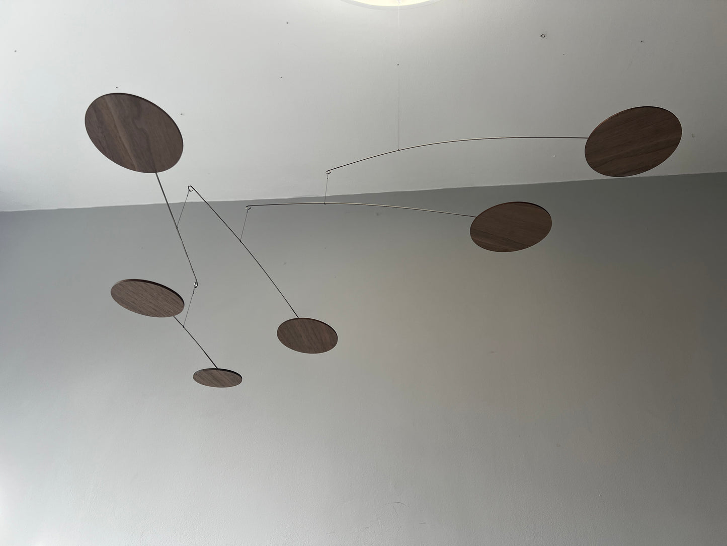 handcrafted walnut mobile by The Illuminist. This elegant modern mobile is made from walnut veneer wooden discs, stainless steel wire, carefully balanced to create gentle, floating motion. it’s the perfect piece of designer home decor for modern interiors. Inspired by Alexander Calder’s mobiles, The Orbit blends art and engineering to form a serene kinetic sculpture that transforms as it moves with the air. make it ideal for mid century decor, Scandinavian design, or any minimalist decor