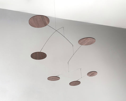 handcrafted walnut mobile by The Illuminist. This elegant modern mobile is made from walnut veneer wooden discs, stainless steel wire, carefully balanced to create gentle, floating motion. it’s the perfect piece of designer home decor for modern interiors. Inspired by Alexander Calder’s mobiles, The Orbit blends art and engineering to form a serene kinetic sculpture that transforms as it moves with the air. make it ideal for mid century decor, Scandinavian design, or any minimalist decor