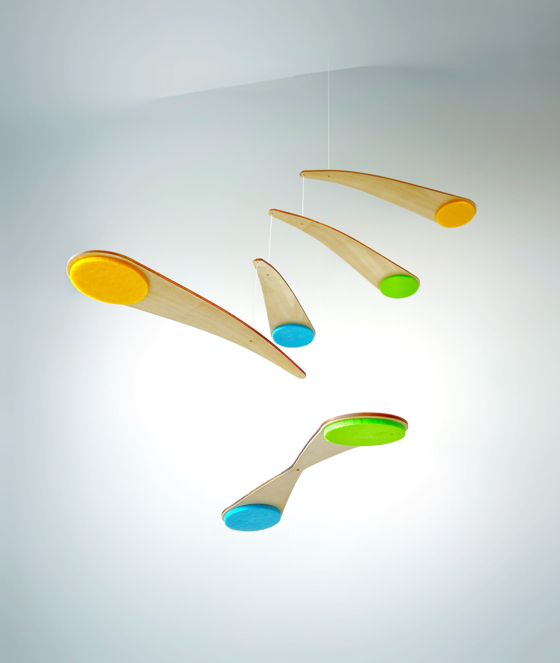 Bo Mobile installed above a baby crib in a modern nursery, featuring custom felt circles and a lightweight wooden frame. This handmade spinning mobile is designed to be viewed from below, creating a soothing, floating effect for babies. Ideal for Scandinavian nursery decor, baby shower gifts, and minimalist baby rooms, this wooden mobile combines gentle motion with clean, contemporary design.