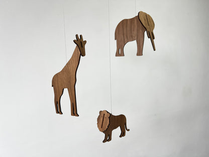 Collection of the three wooden animals used in the African animal mobile including elephant mobile, giraffe mobile and lion mobile pieces. Each animal is crafted from engineered walnut wood with smooth edges and visible grain, ready to be assembled into a balanced hanging mobile. Designed as a baby mobile for nursery decor above a cot or crib, the finished wooden mobile creates a calming safari themed Africa mobile inspired by Flensted mobile style. A unique handmade baby gift & timeless mobile.