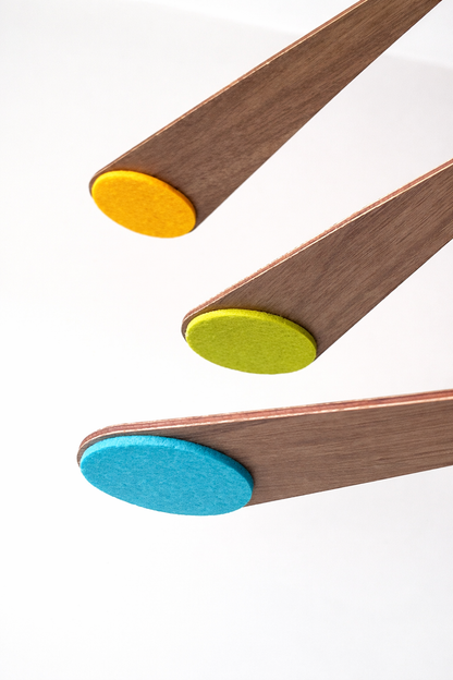 in pastel shades this alternative baby mobile in rich walnut wood, featuring curved forms and a floating kinetic structure. This handcrafted nursery decor piece rotates gently, creating a peaceful sensory experience for babies. Inspired by vintage mid century modern design, it works in minimalist and design-led homes. A unique heirloom gift with custom colours available.
