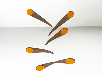 Alternative baby mobile in rich walnut wood, featuring curved forms and a floating kinetic structure. This handcrafted nursery decor piece rotates gently, creating a peaceful sensory experience for babies. Inspired by vintage mid century modern design, it works in minimalist and design-led homes. A unique heirloom gift with custom colours available.
