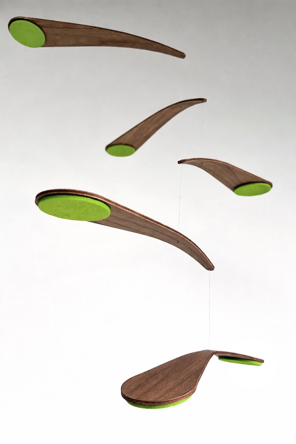 in lime green this mid century modern inspired walnut crib mobile with a balanced five-tier structure and smooth flowing shapes. This kinetic sculpture moves gently, creating a calming visual rhythm for babies. Perfect for alternative nurseries or stylish interiors, it blends art and function. Handmade from quality materials with custom colours available.