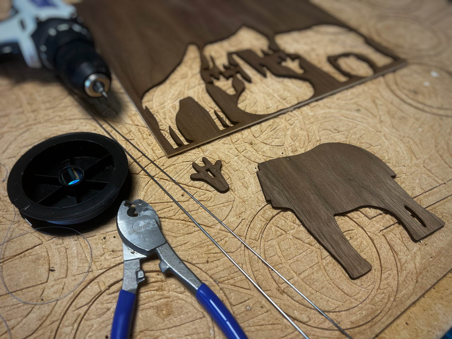 Behind the scenes view of the handmade wooden animal mobile being prepared in the workshop. The elephant mobile, giraffe mobile and lion mobile pieces are cut from engineered walnut wood before being assembled into a balanced hanging mobile. This process highlights the craftsmanship behind the African animal baby mobile designed for nursery decor above a cot or crib. Inspired by classic Flensted mobile design principles, this wooden mobile becomes a beautiful Africa mobile and meaningful gift