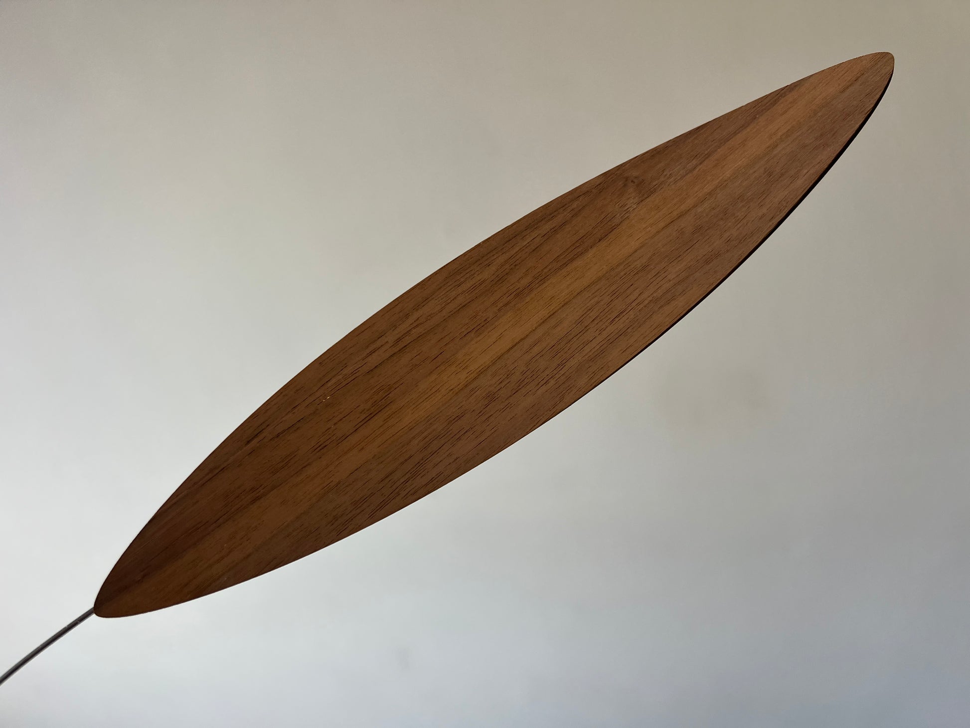 Large 1 metre walnut leaf mobile hanging on a wall beside artist, handcrafted layered walnut veneer wooden mobile with curved leaf forms and stainless steel wire, modern kinetic sculpture, moving art for adults, mid century decor, Scandinavian design minimalist decor, Calder inspired art mobile, unique designer home decor, wood hanging art for living room, gallery wall decor, contemporary mobile handmade in the UK by The Illuminist, soothing balancing art and modern wood art