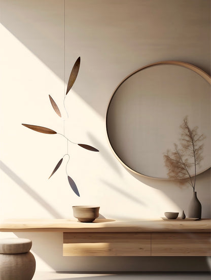 Large 1 metre walnut leaf mobile hanging on a wall beside artist, handcrafted layered walnut veneer wooden mobile with curved leaf forms and stainless steel wire, modern kinetic sculpture, moving art for adults, mid century decor, Scandinavian design minimalist decor, Calder inspired art mobile, unique designer home decor, wood hanging art for living room, gallery wall decor, contemporary mobile handmade in the UK by The Illuminist, soothing balancing art and modern wood art