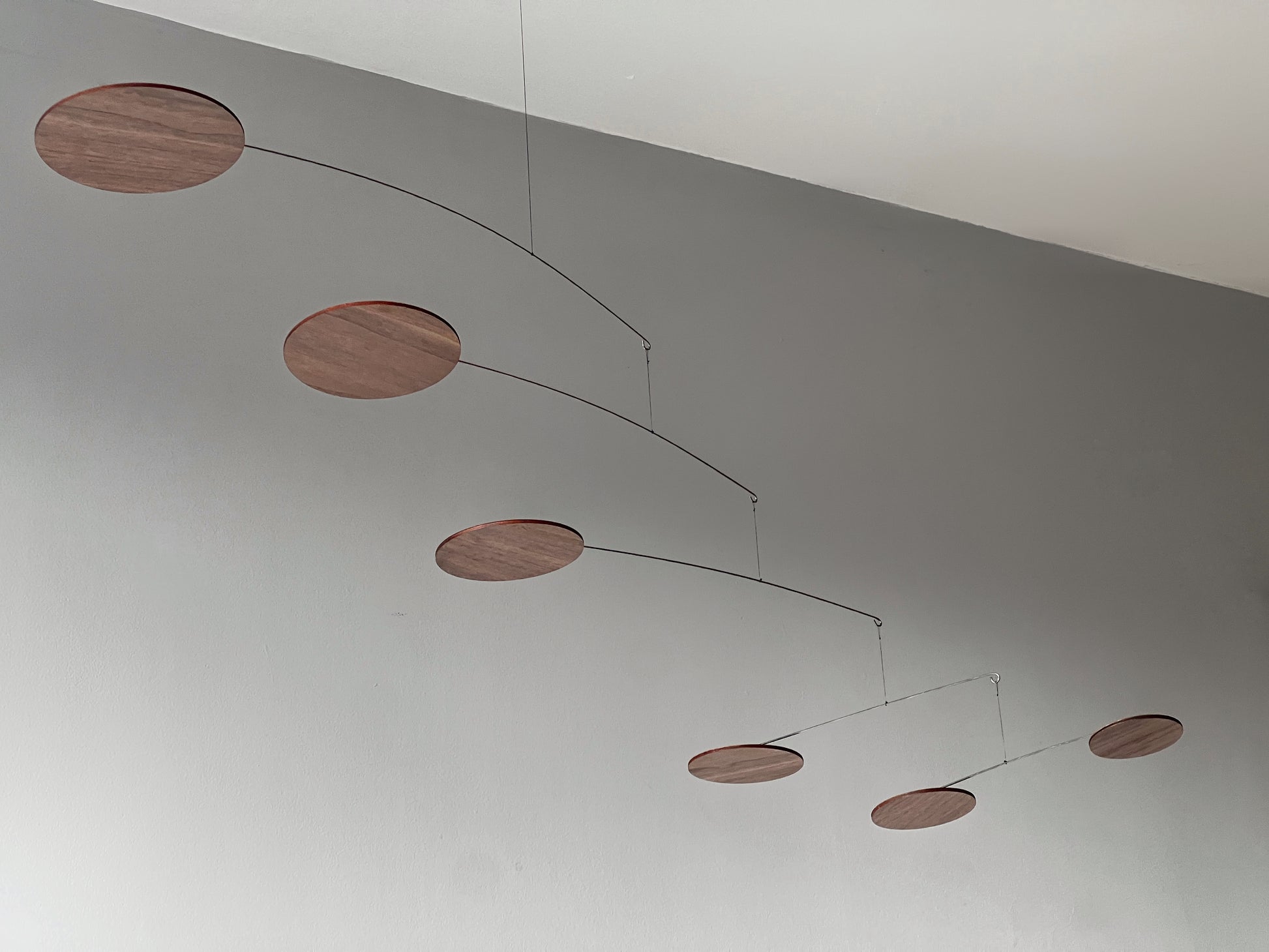 handcrafted walnut mobile by The Illuminist. This elegant modern mobile is made from walnut veneer wooden discs, stainless steel wire, carefully balanced to create gentle, floating motion. it’s the perfect piece of designer home decor for modern interiors. Inspired by Alexander Calder’s mobiles, The Orbit blends art and engineering to form a serene kinetic sculpture that transforms as it moves with the air. make it ideal for mid century decor, Scandinavian design, or any minimalist decor