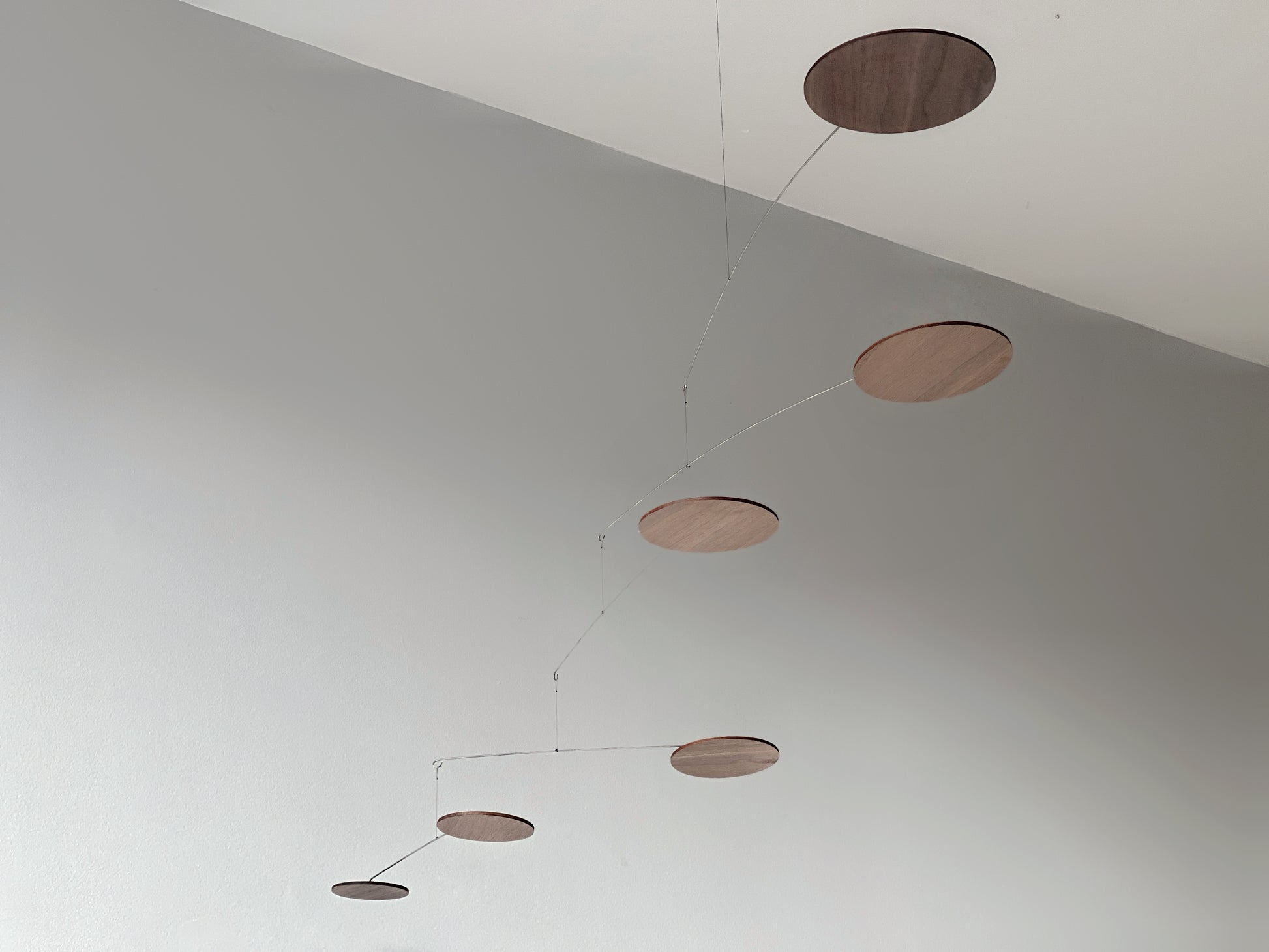 handcrafted walnut mobile by The Illuminist. This elegant modern mobile is made from walnut veneer wooden discs, stainless steel wire, carefully balanced to create gentle, floating motion. it’s the perfect piece of designer home decor for modern interiors. Inspired by Alexander Calder’s mobiles, The Orbit blends art and engineering to form a serene kinetic sculpture that transforms as it moves with the air. make it ideal for mid century decor, Scandinavian design, or any minimalist decor
