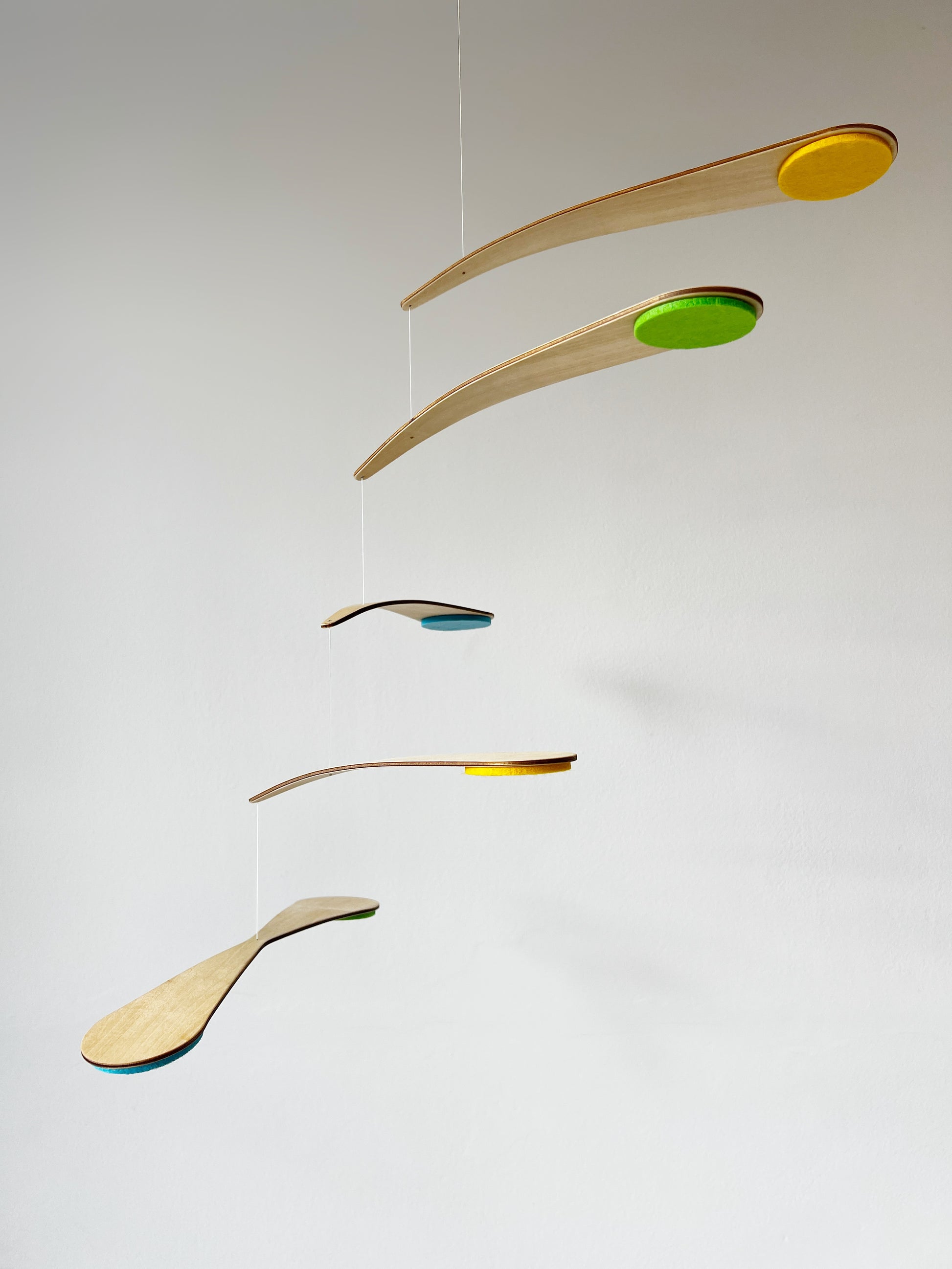 Close-up view of the Bo Mobile nursery mobile showing natural wood arms and wool felt circles in custom colours, carefully balanced to create a floating kinetic effect. This handmade baby mobile is designed to be viewed from below, just like a baby lying in a crib. Perfect for modern nursery decor, Montessori-inspired baby rooms, and minimalist interiors, this spinning mobile brings gentle motion and soft colour to a calm, stylish nursery space.