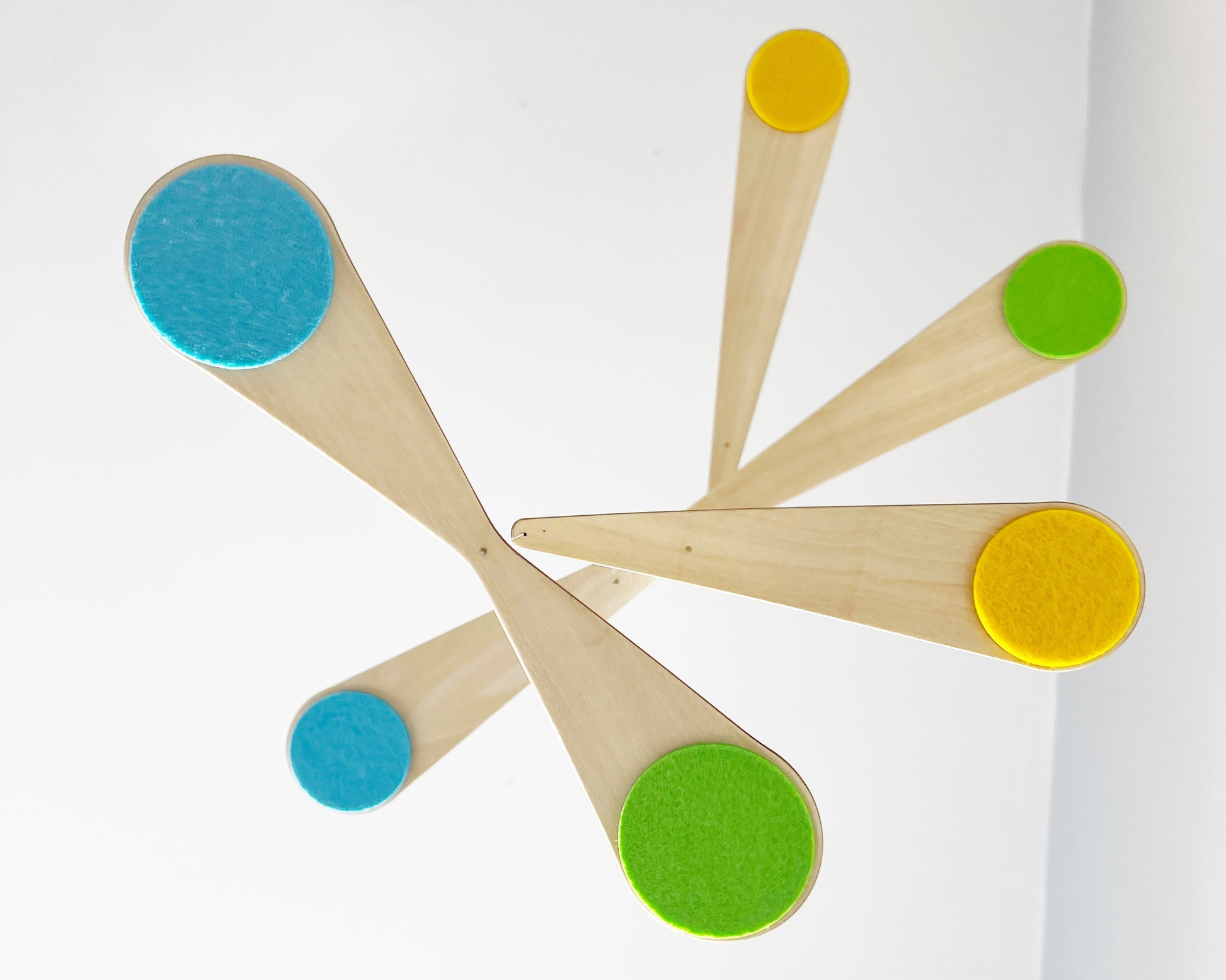 Bo Mobile hanging freely against a neutral background, showcasing its sculptural curved wooden arms and soft felt circles. This modern baby mobile is designed to float and spin gently, creating a calming visual experience for babies in their crib. Ideal for Scandinavian nursery decor, gender-neutral baby rooms, and minimalist interiors, this handmade wooden mobile blends art, movement, and function beautifully.