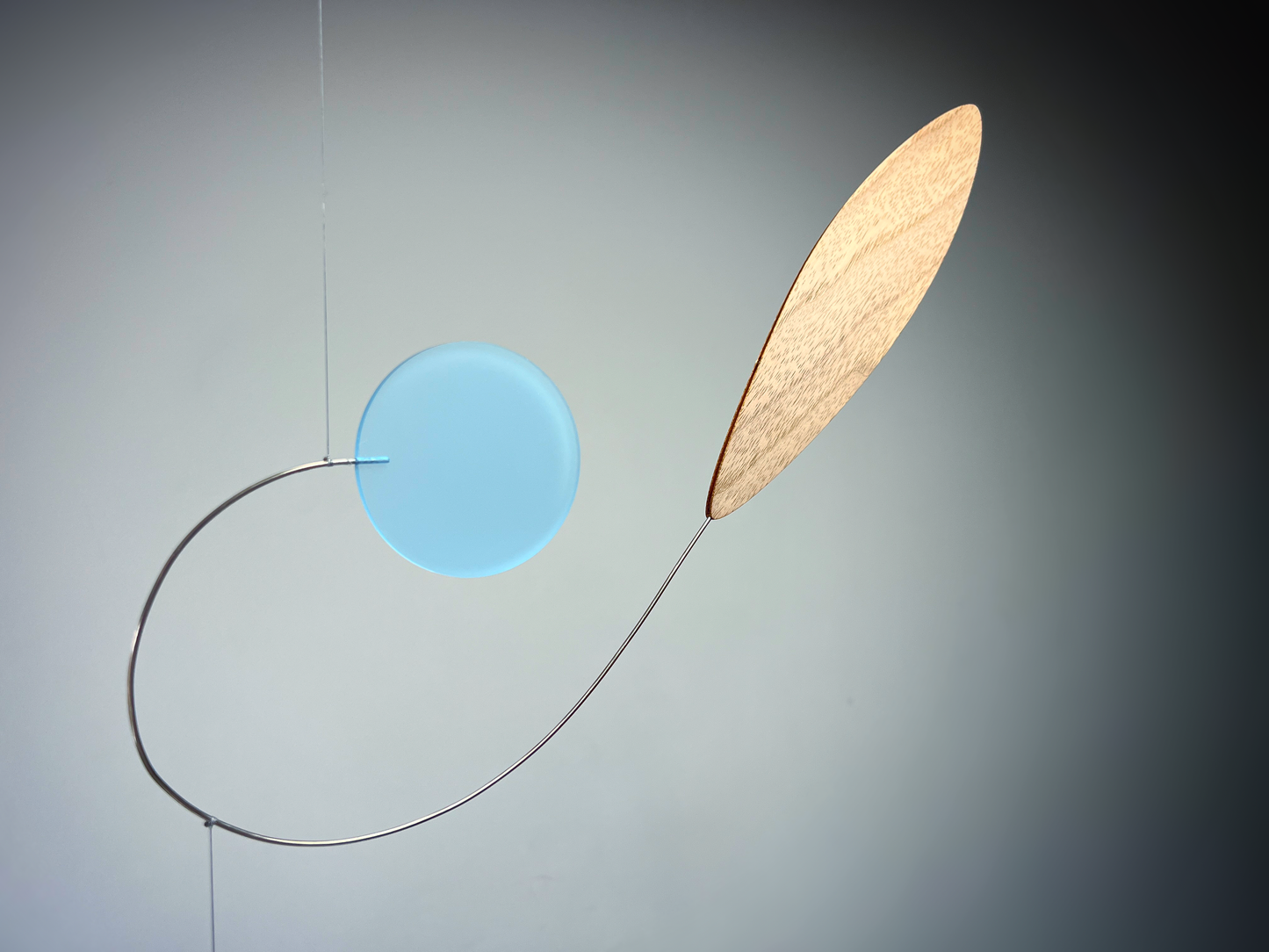 Modern pendant light with a blue shade and wooden diffuser on a gray background Rise MOBILE - Mid century Kinetic mobile sculpture In walnut and acrylic 