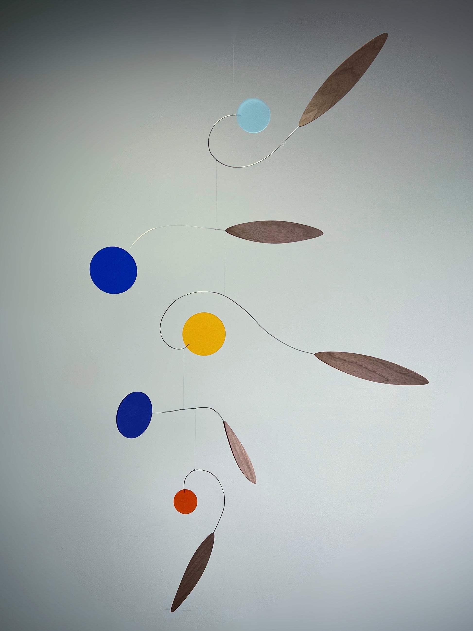 Colorful abstract mobile hanging against a plain background Rise MOBILE - Mid century Kinetic mobile sculpture In walnut and acrylic 