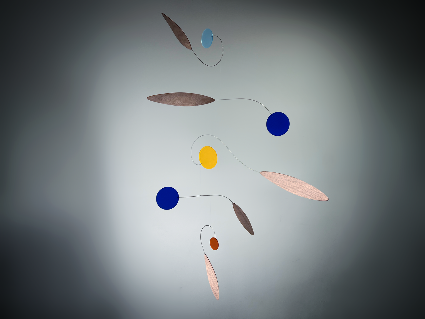 Colorful mobile with circular and leaf-shaped objects on a gray background Rise MOBILE - Mid century Kinetic mobile sculpture made of walnut and acrylic 