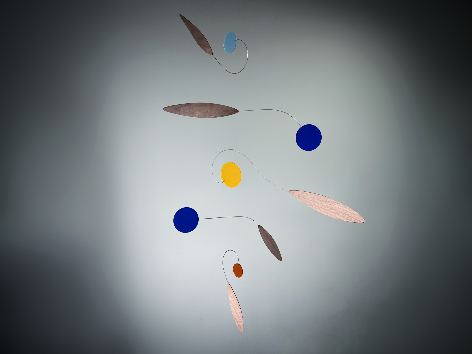 Colorful mobile with circular and leaf-shaped objects on a gray background Rise MOBILE - Mid century Kinetic mobile sculpture made of walnut and acrylic 